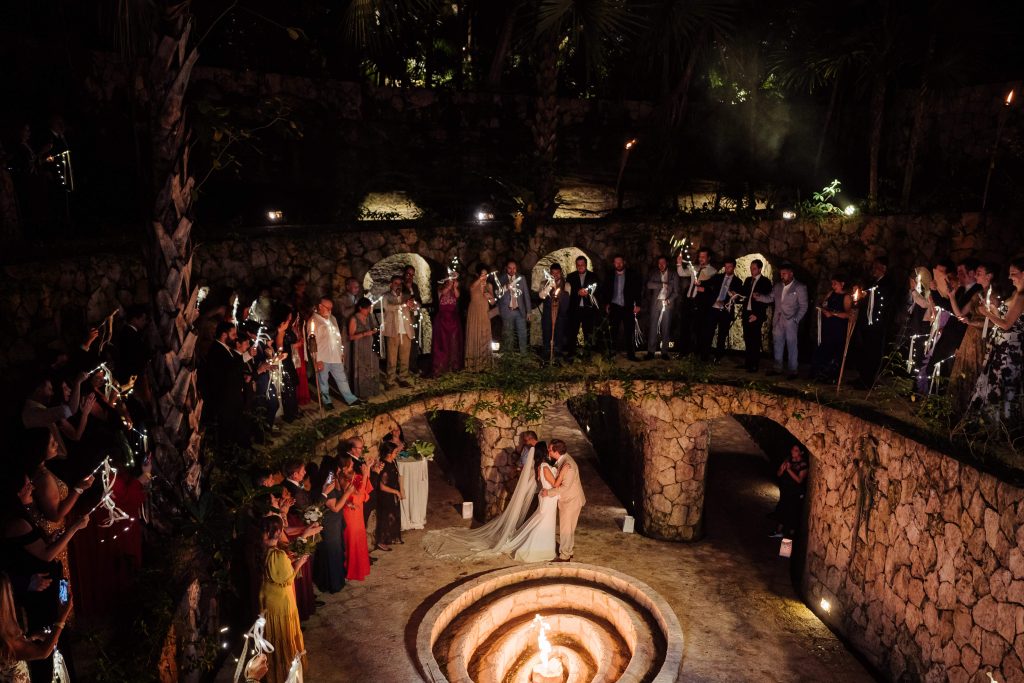 bride and groom kissing in the caracole at Xcaret park following the words I do at their wedding ceremony captured by Xcaret Wedding Photographer Pixan